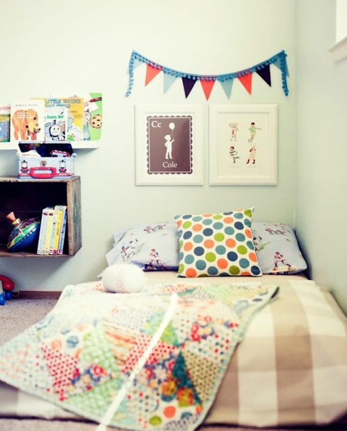 mur couleur blanche, coussins et couverture de lit multicolores, deco murale, dessins, etagere rangement livres, meuble bas, exemple chambre montessori