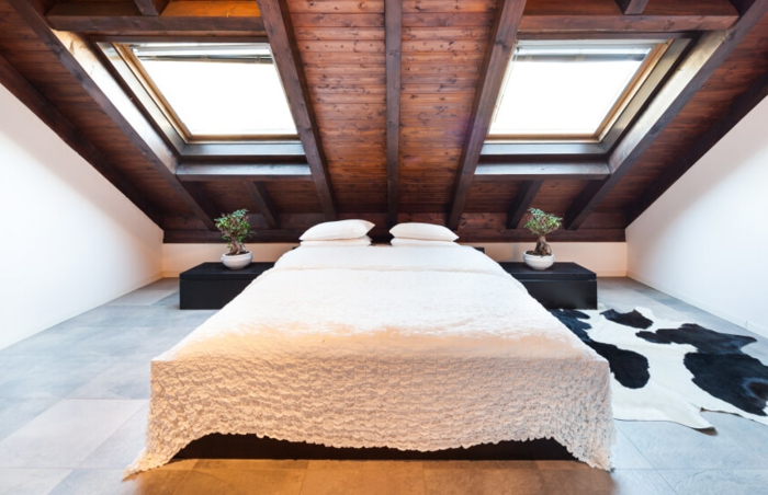 carrelage effet bois, couverture de lit blanche, tapis vache, peinture mur blanchem plafond en bois marron, fenêtres de combles, amenagerment combles
