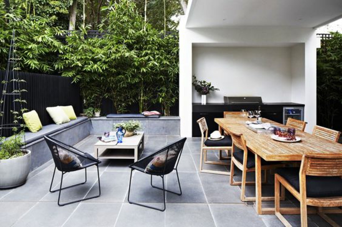 une élégante cuisine d'été couverte en noir, terrasse accueillante d'un aménagement fonctionnelle
