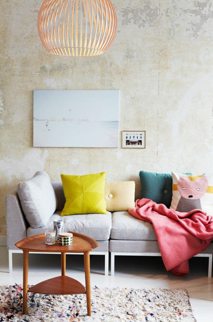 salon gris et jaune, coussins déco et sofa gris, table basse en bois, mur effet béton