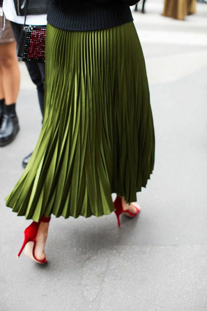 tenue chic avec jupe plissée longue couleur olive portée avec des chaussures rouges à talons aiguilles