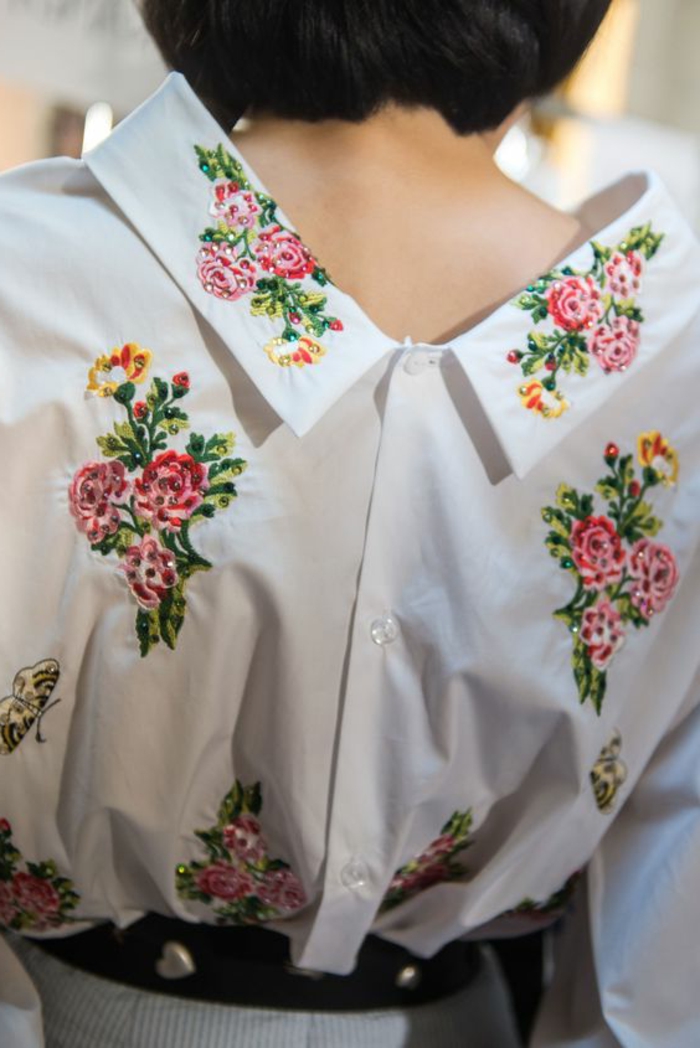 tenue chic blouse blanche au col claudine avec des fleurs brodés et ceinture noire à coeurs métalliques