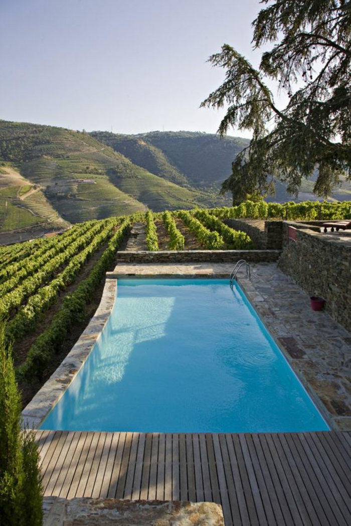 belle piscine à niveaux qui surplombe une vigne, entourage piscine en pierre naturelle et bois