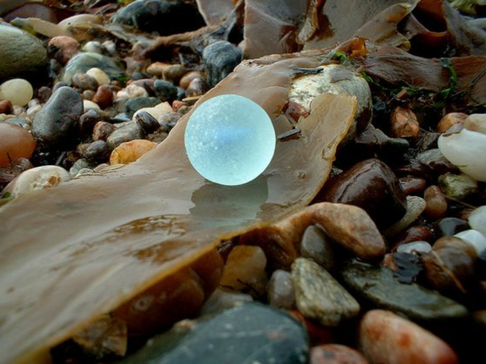 boule de verre de mer bleue au sein des cailloux sur la plage 