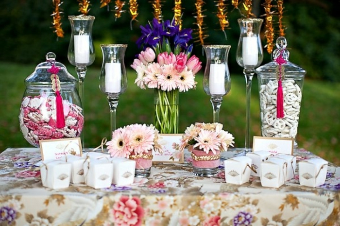 bonbons de sucre, bouquets de fleurs de tailles diverses, bougeoirs, nappe à motifs floraux, cadre naturel, mariage en plein air