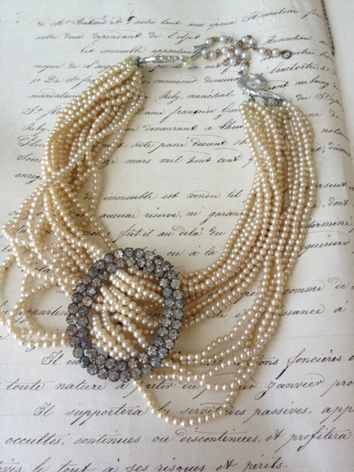 collier de perles avec un grand élément ovale devant en pierres synthétiques blanches