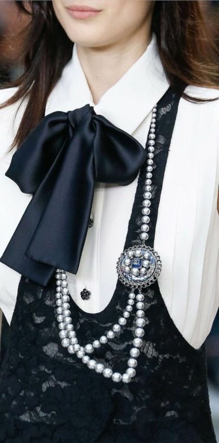 collier en perles en noir et blanc avec grand noeud noir et chemisier au col blanc 