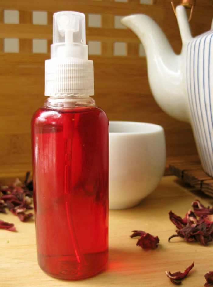 coloration-bio-végétale-thé-hibiscus-théière-rayée-tasse-à-thé-blanche préparer un spray capillaire pour une coloration naturelle des cheveux roux, intensifier les reflets rouges avec infusion aux fleurs d'hibiscus