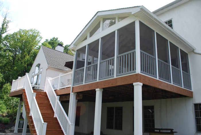 terrasse surélevée, maison à façade blanche, escalier en bois, rambarde blanche, fenêtres à carreaux