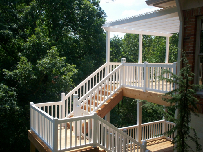 terrasse sur pilotis, arbres, escalier en bois, auvent en bois peint en blanc, façade en briques