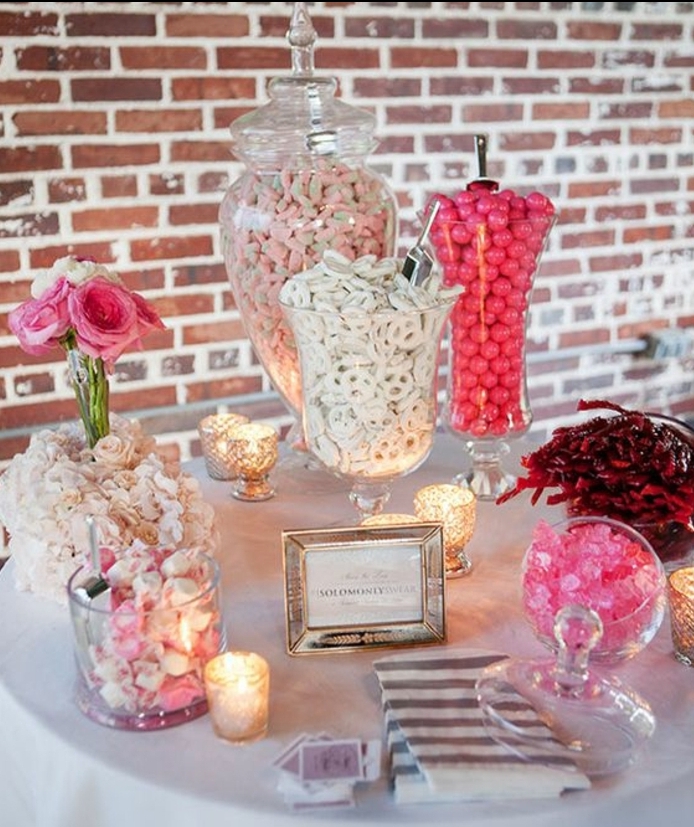 bar à bonbons mariage, nappe blanche, dragées et boules de gomme et bonbons de sucre en rose et blanc, cadre photo argenté, bougeoirs en verre, table de fond en briques