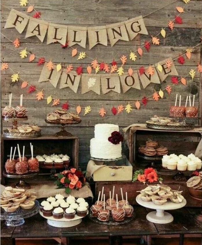 decoration bar a bonbon, cupcakes, sablés, tartalettes, pommes d amour chocolat, gateau à deux étages, guirlande de feuilles mortes en papier, et guirlande en tissu intéressant, table en bois, mariage vintage rustique