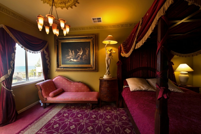 chambre boudoir, lit violet, cantonnière violet avec franges dorés, lampe de chevet jaune, grande peinture