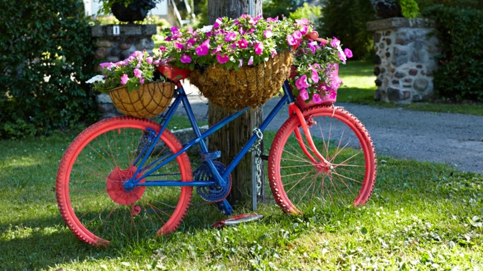 decoration de jardin a faire soi meme, gazon vert, vélo en bleu et rouge, support de fleurs diy