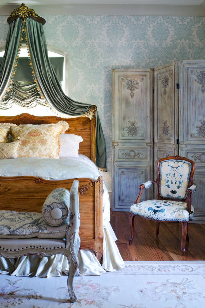 amenagement chambre, murs damassés en bleu, rideaux verts, lit en bois, coussins orange, chaise en bois
