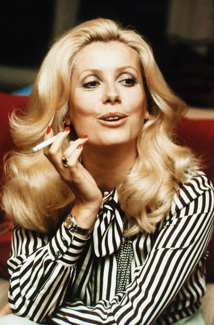 look-années-60-Catherine-Deneuve-chemise-rayée-et-cheveux-loose-ondulants look années 60, coiffure bouclée de Catherine Deneuve habillée en une chemise rayée