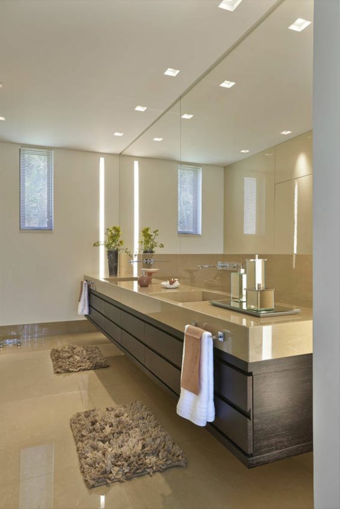 miroir lumineux salle de bain sur le mur entier avec un meuble suspendu sur toute la longueur