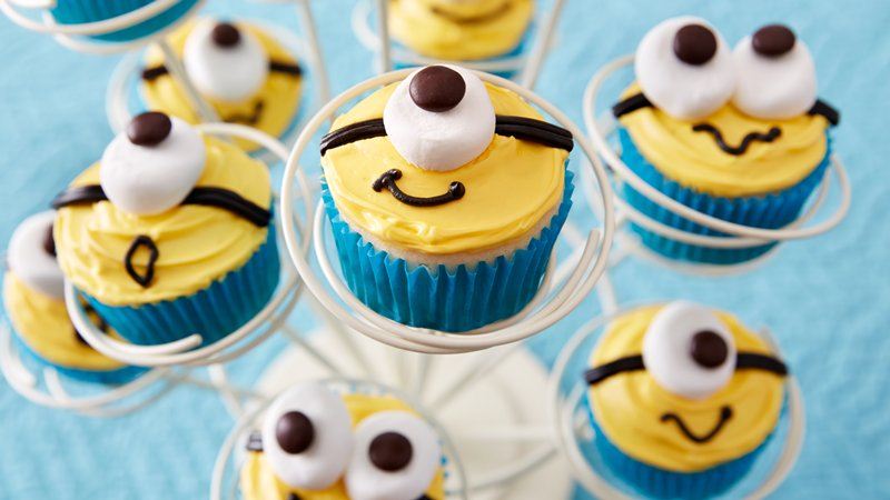 idée de cupcakes minions, glaçage jaune, guimauve en guise d oeil, décoration chocolat, caissette cupcake bleue