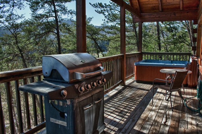 terrasse bois surélevée, chaise en fer forgé, auvent avec poutres en bois, jacuzzi, barbecue, table ronde
