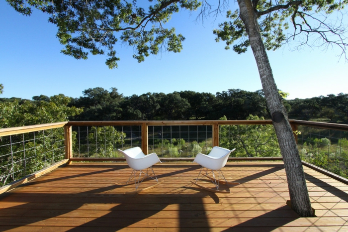 terrasse surélevée, chaises blanches, arbres, vue sur la forêt, rambarde en bois, arbres