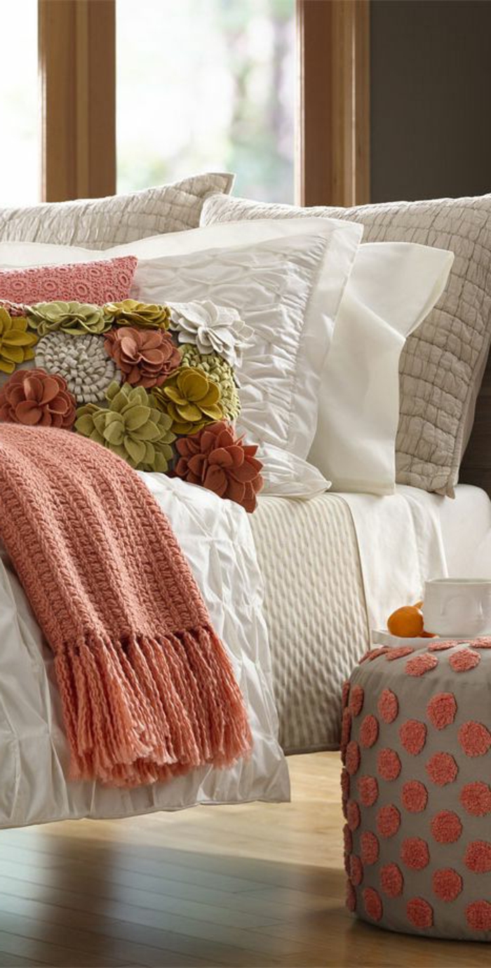 plaid de lit couleur abricot, tabouret gris à pois roses, coussins en rose corail et blanc