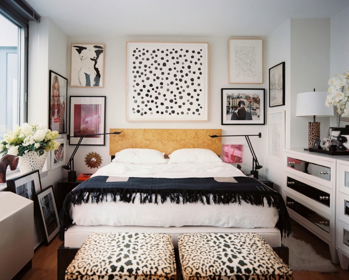 mur de cadres, chambre à coucher blanche, parquet en bois, tapis moelleux blanc, plaid noir avec franges