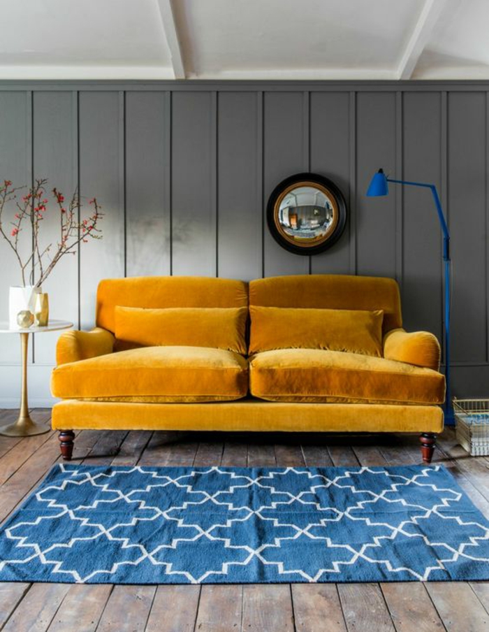 un canapé velours deux place couleur moutarde combiné ave un tapis graphique bleu