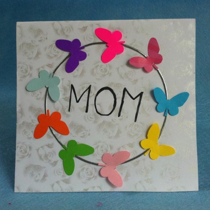 carte fête des mères à fabriquer, papillons qui volent en cercle collées sur un carré de papier à petits roses