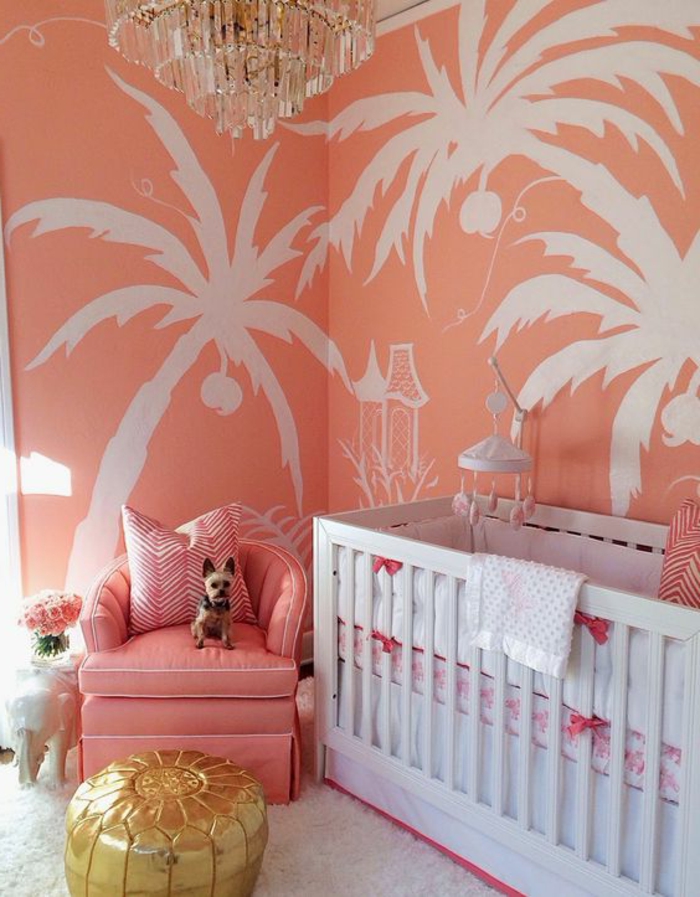 chambre d'enfant mur couleur saumon, palmiers blancs peints sur les murs, fauteuil rose et plafonnier en cristal