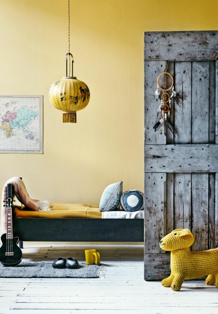 une chambre d'enfant de style vintage peint en ocre jaune doré, porte en bois rustique à effet vieilli, tendance déco ocre