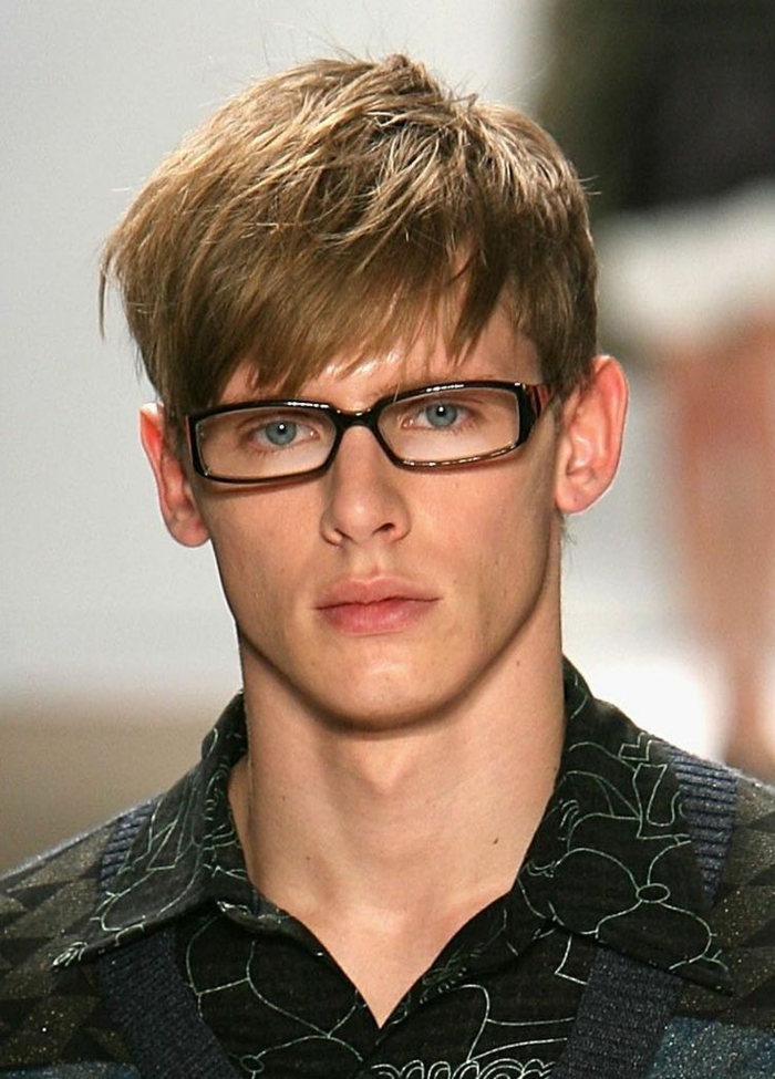 coupe garcon courte et coiffure avec frange asymetrique qui tombe sur le front, lunettes de vue, garçon blond