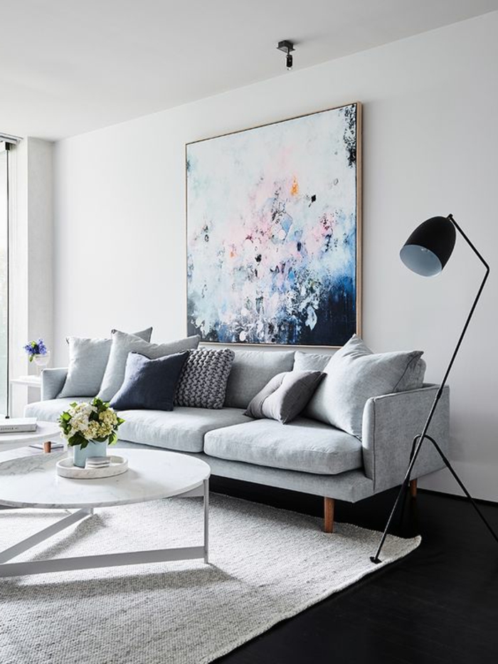 couleur assortie au gris, table blanche, sofa gris clair, lampe de sol noire, peinture murale gris perle