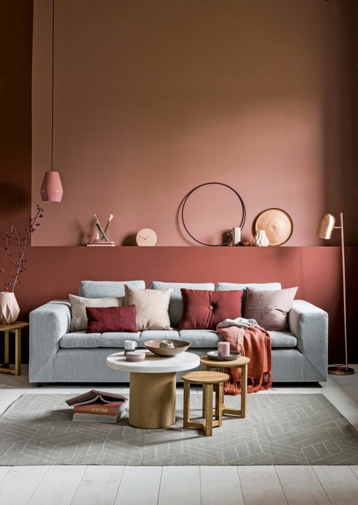 mur couleur saumon, sofa gris, table basse, tabourets de bois, lampe pendante rose