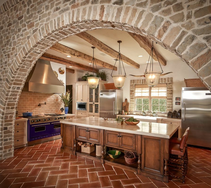 cuisine équipée, carrelage marron, mur en briques, plafond blanc, four électrique violette, réfrigérateur en argent