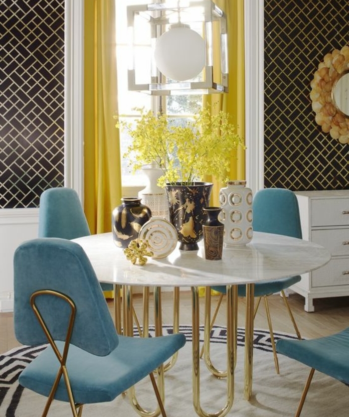 table en marbre et pieds dorés, chaises deco bleu canard, rideaux jaunes, mur à rectangles noirs, decoration orientale en jaune et bleu