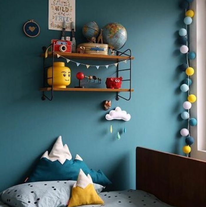 deco bleu canard dans une chambre enfant, accents jaunes, guirlande de boules, coussins en forme de montagne jaune et bleu, etagere murale en bois et metal, jiuets