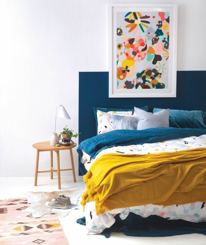 exemple de deco bleu canard, tete de lit et linge de lit couleur bleue, tapis à motifs géométriques, tableau coloré, table de nuit scandinave, couverture de lit jaune, deco murale abstraite