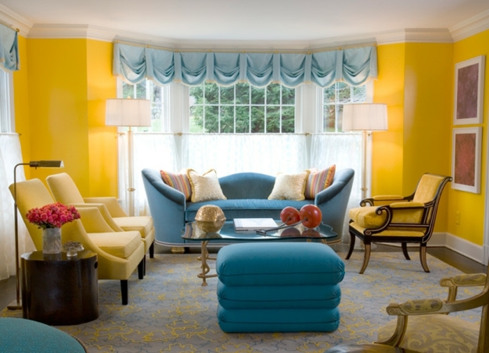 exemple de salon classique, mur couleur jaune imperial, avec des fauteuils jaunes, canapé et tabouret bleus, tapis gris, deco bleu et jaune