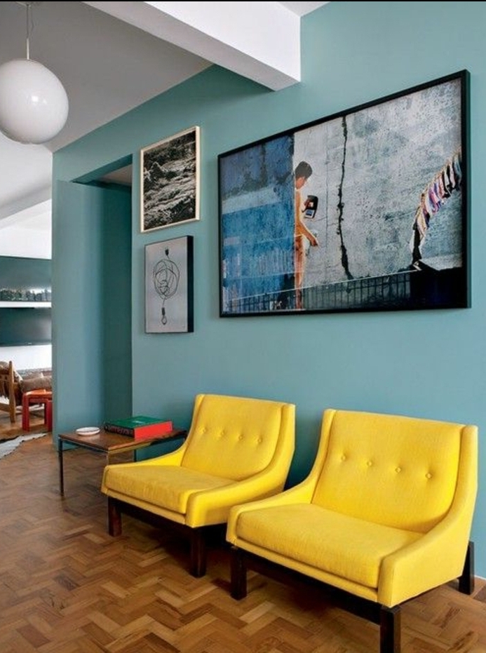 idee deco bleu et jaune, tonalité pastel, fauteuils jaunes sur le fond d un mur décoré de tableaux artistiques, parquet clair