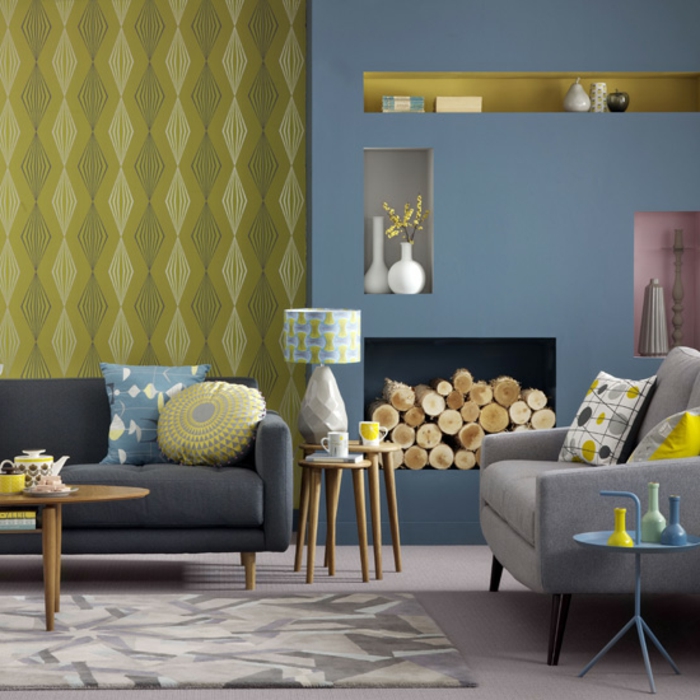 exemple deco bleu et jaune, canape gris anthracite et fauteuil gris, coussins multicolores, cheminée, table basse en bois, papier peint jaune et mur d accent bleu gris