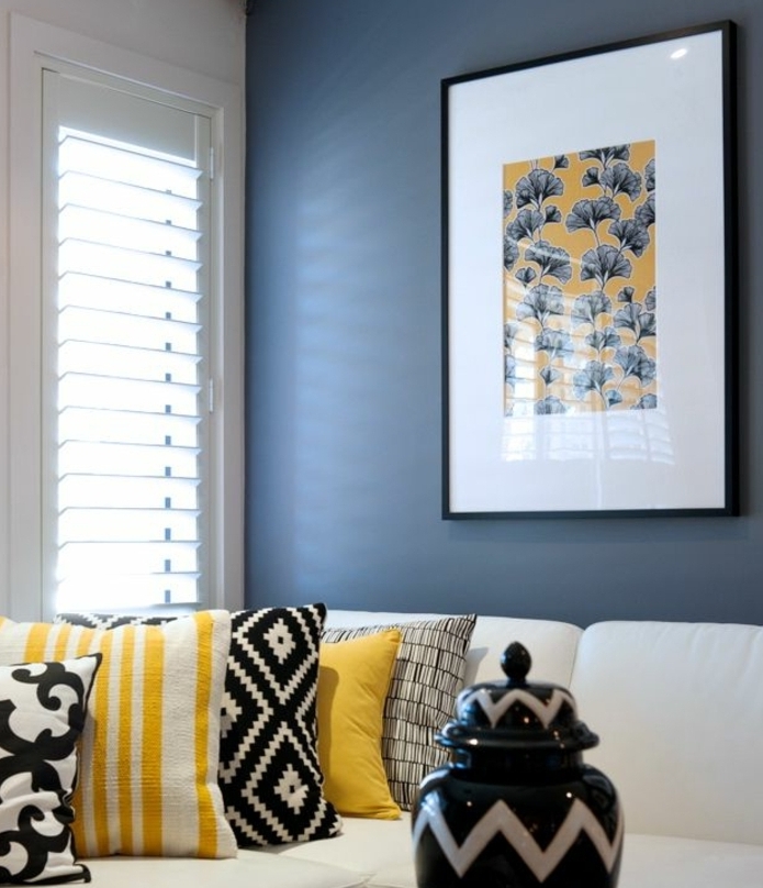 idee deco bleu et jaune, coussins en jaune, noir et blanc, canapé blanc, mur couleur bleue, decoration murale fleurs