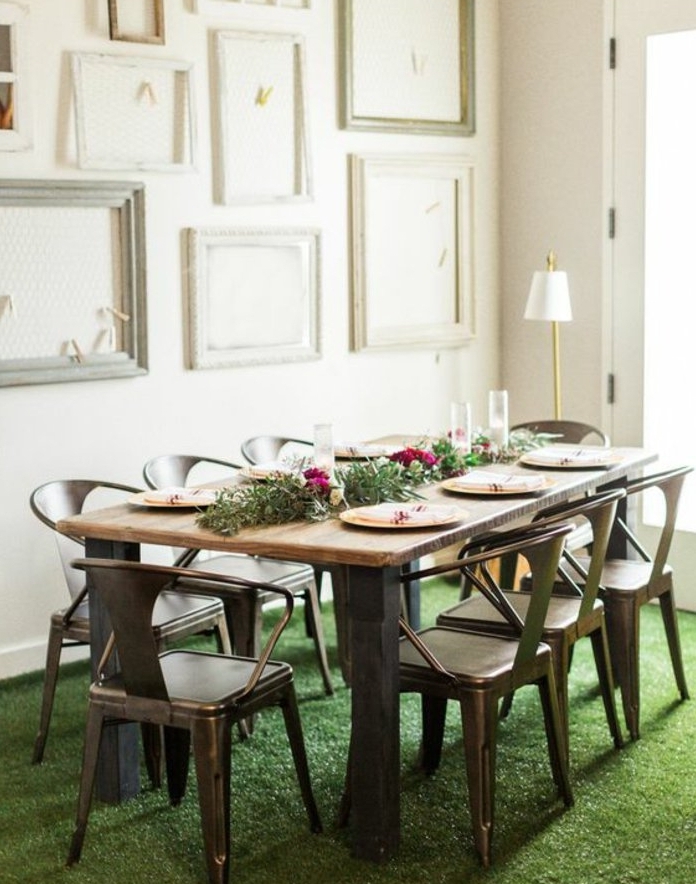 habiller un mur de cadres vides blancs et gris, chaises en métal, table rustique en bois, centre de table floral et assiettes, revêtement sol, imitation herbe fraîche