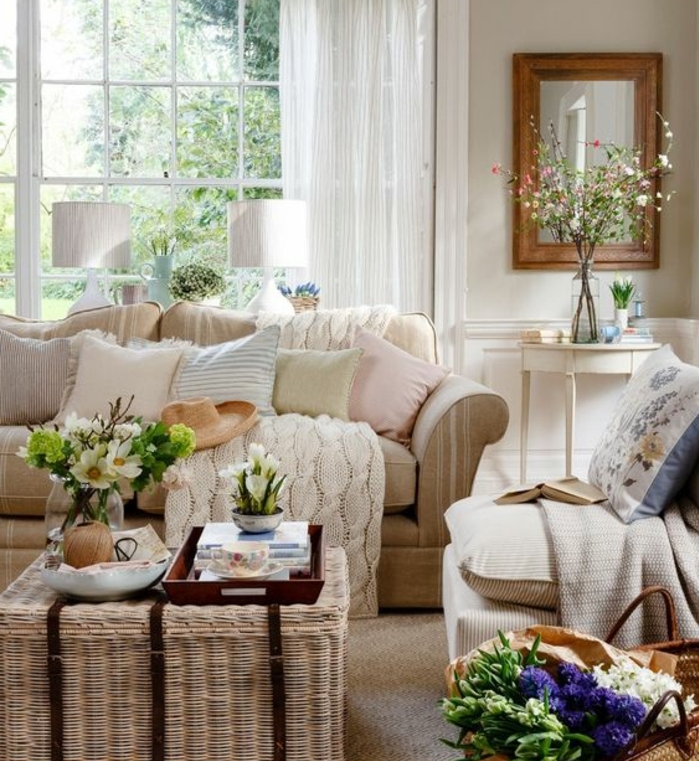 exemple deco campagne chic, table basse en rotin, canapéet fauteuil beige, coussins couleurs pastel, plaid et decoration fleurs