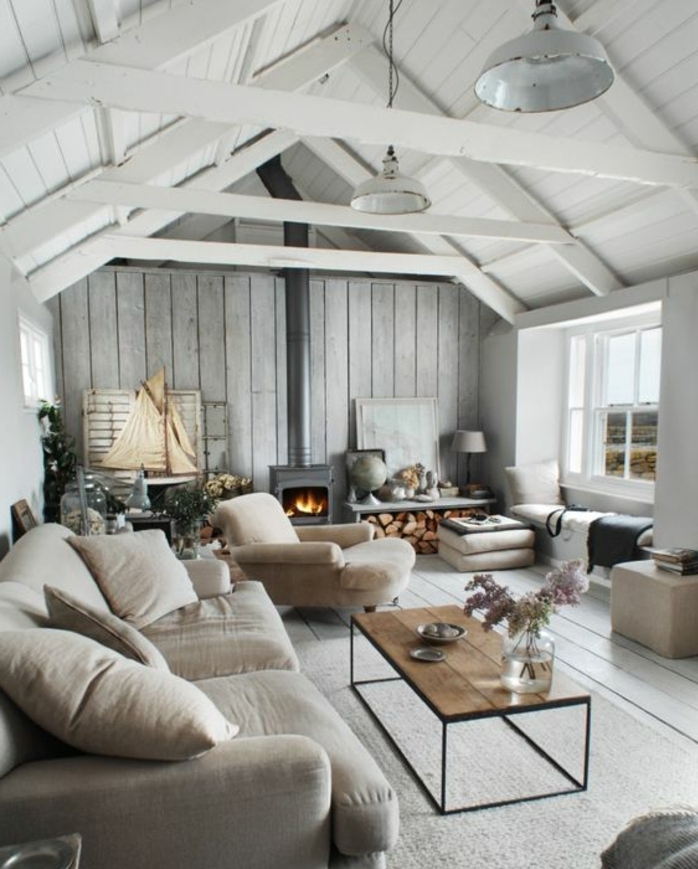 canapé et chaise longue gris, tapis gris clair, table basse en bois et métal. cheminee moderne, style scandinave, suspensions industruelles, toiture bois blanc, salon rustique