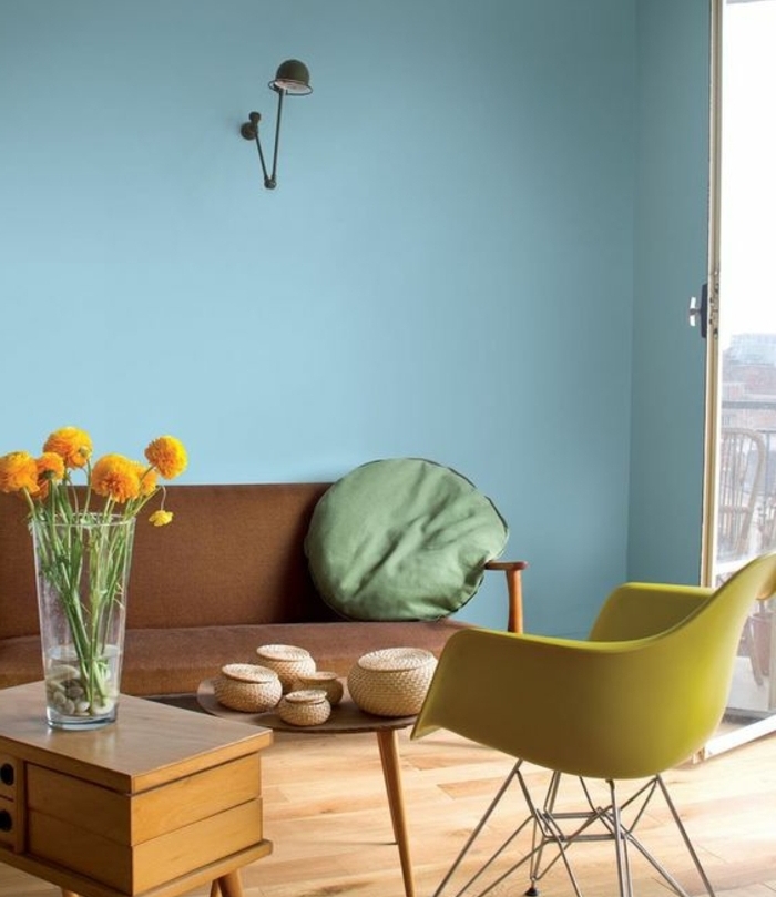 deco salon scandinave, chaise nordique jaune et couleur mur bleu pastel, table basse en bois, canapé marron, coussin vert
