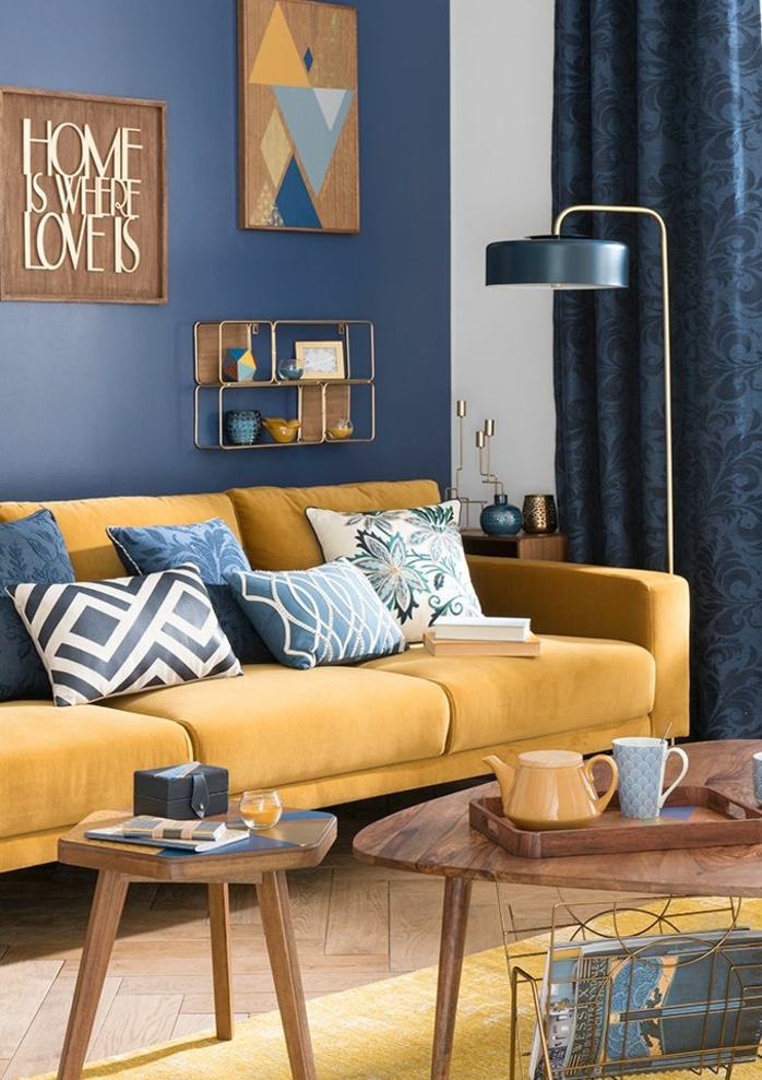 deco bleu et jaune, salon scandinave, canapé jaune moutarde, decoration murale en bois, mur couleur bleu foncé, parquet clair, tables basses en bois, lampe design