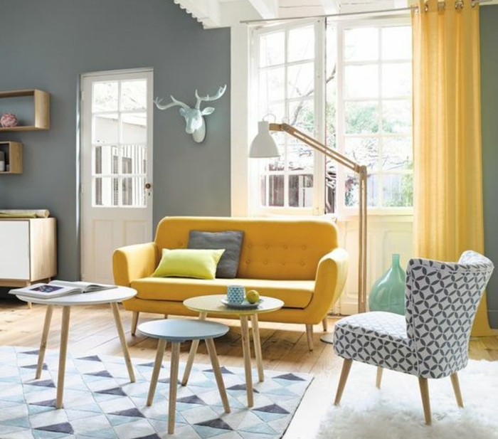 deco salon scandinave, rideau et canapé jaune, table basse et tapis à motifs géométriques bleus, tapis de fourrure blanc, parquet clair