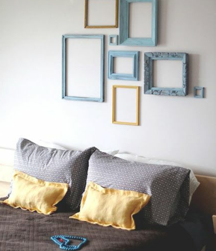 idee comment décorer une chambre a coucher design, mur de cadres bleus et jaunes, lit en bois, couverture de lit gris et jaune