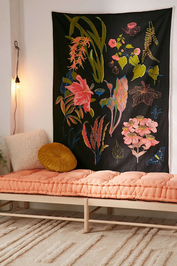 un coin repos d'ambiance bohème chic, canapé sans dossier rose de pêche décoré d'un coussin ronde couleur ocre jaune moutarde, tapis mural à motifs végétaux