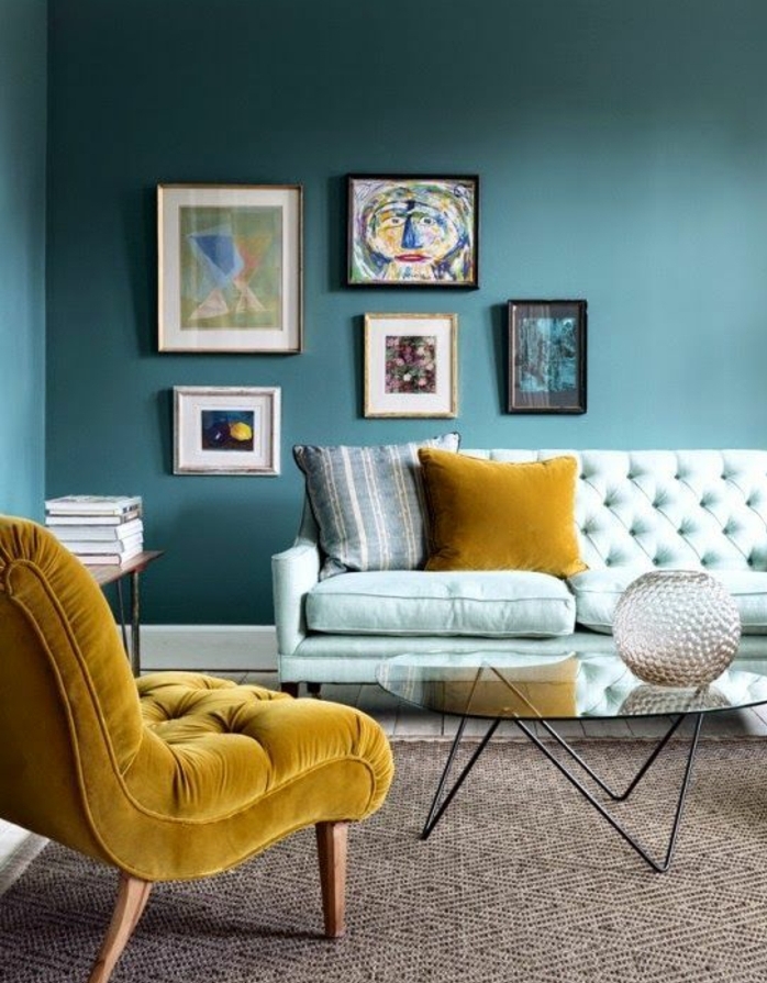 idee deco bleu canard couleur peinture, fauteuil et coussin jaune, tapis bleu clair, tapis marron, table basse en bois et métal, decoration murale tableaux abstraits